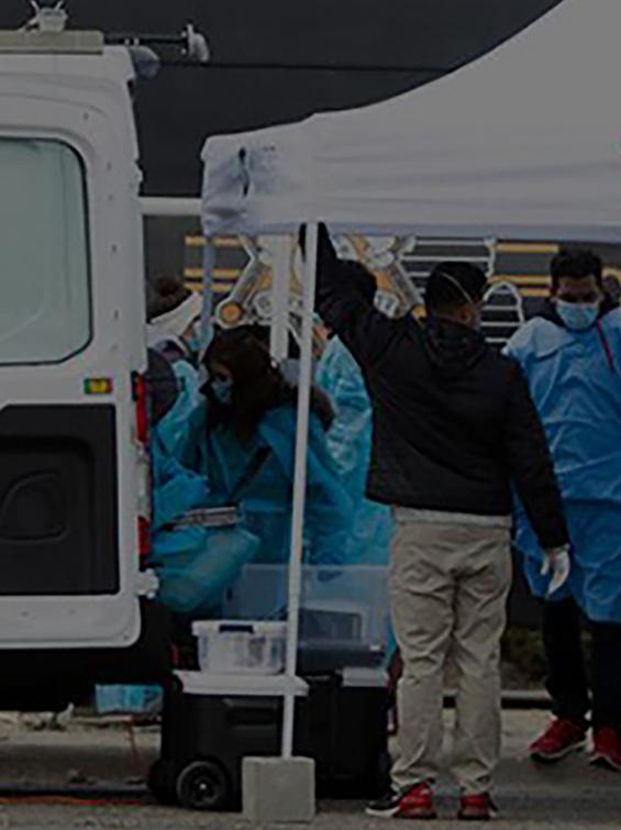 Van and tent with badging and people getting tested for covid