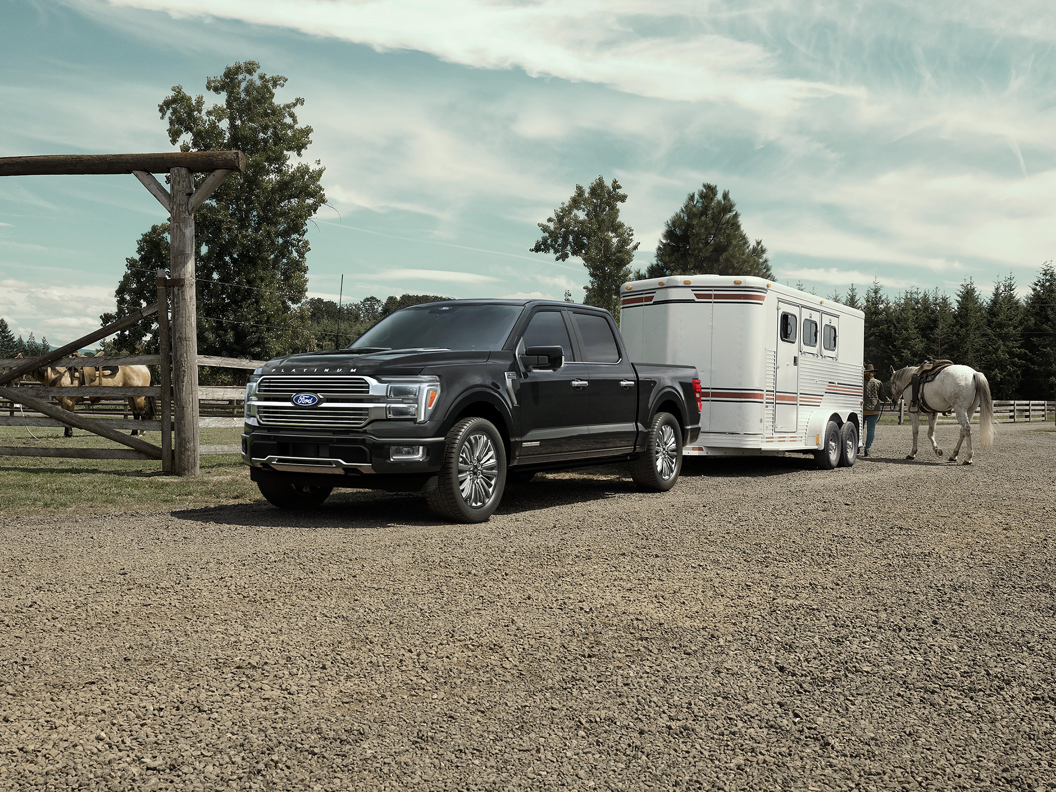 2025 Ford F-150® Platinum® in Agate Black parked with a trailer on a horse farm