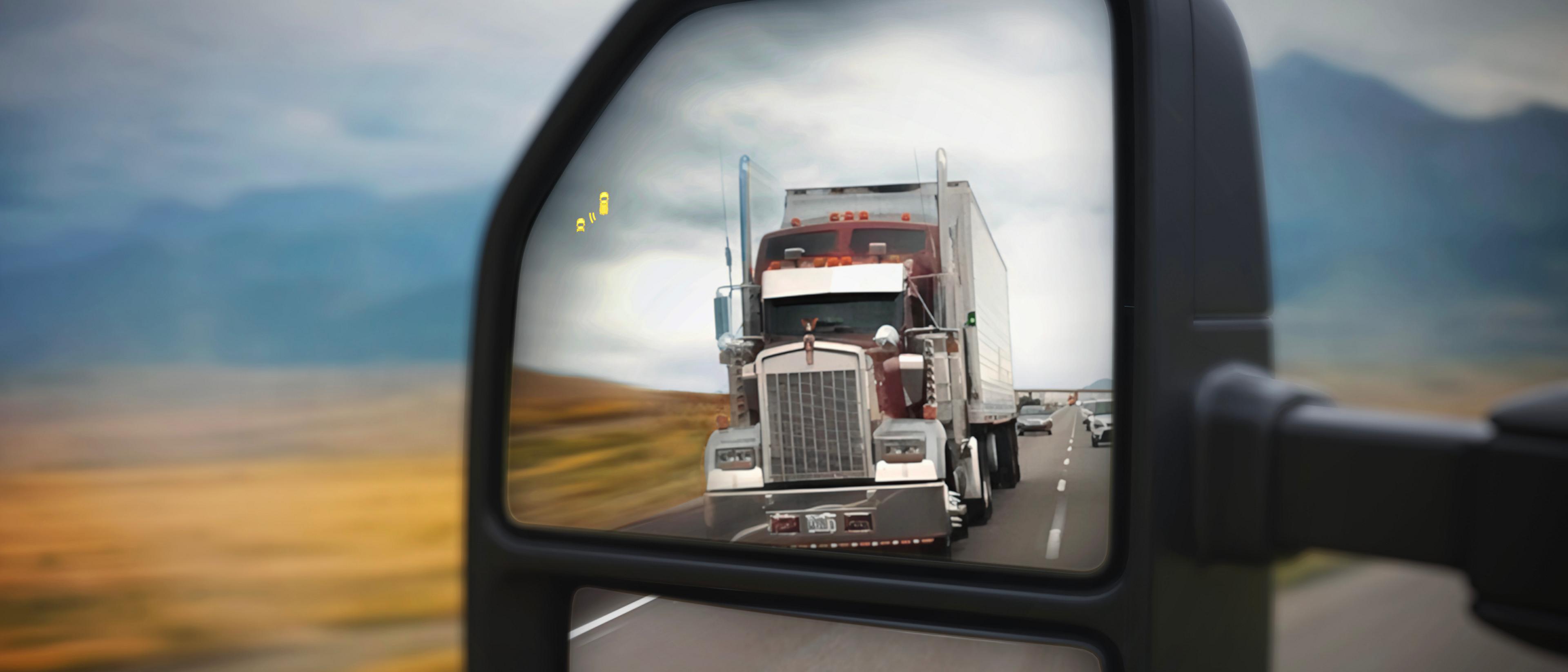 View of the 2027 Ford Super Duty® pickup left side view mirror with a semi truck in the reflection