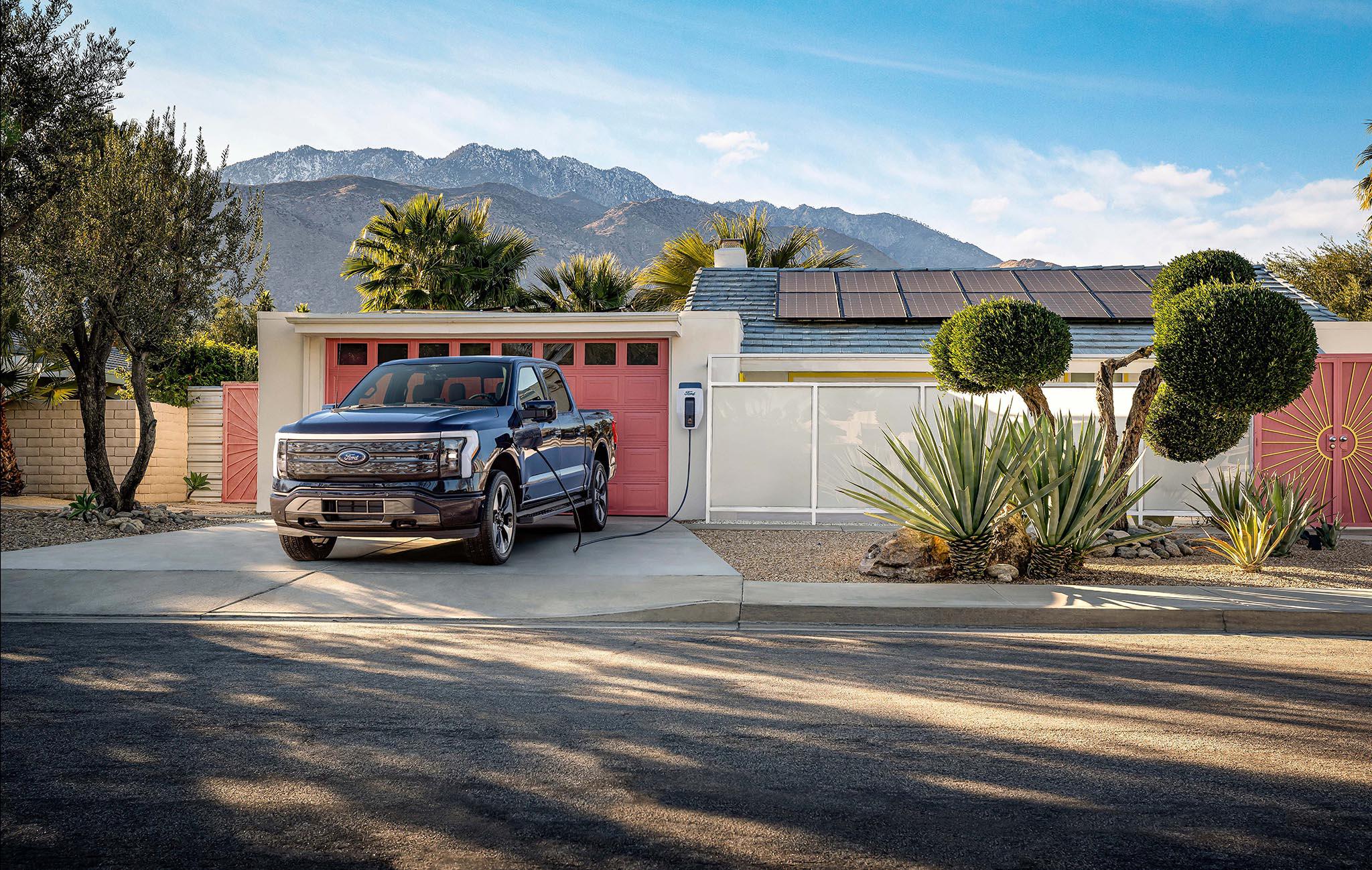 Ford F-150 Lightning truck in driveway while plugged into a Ford Charge Station Pro
