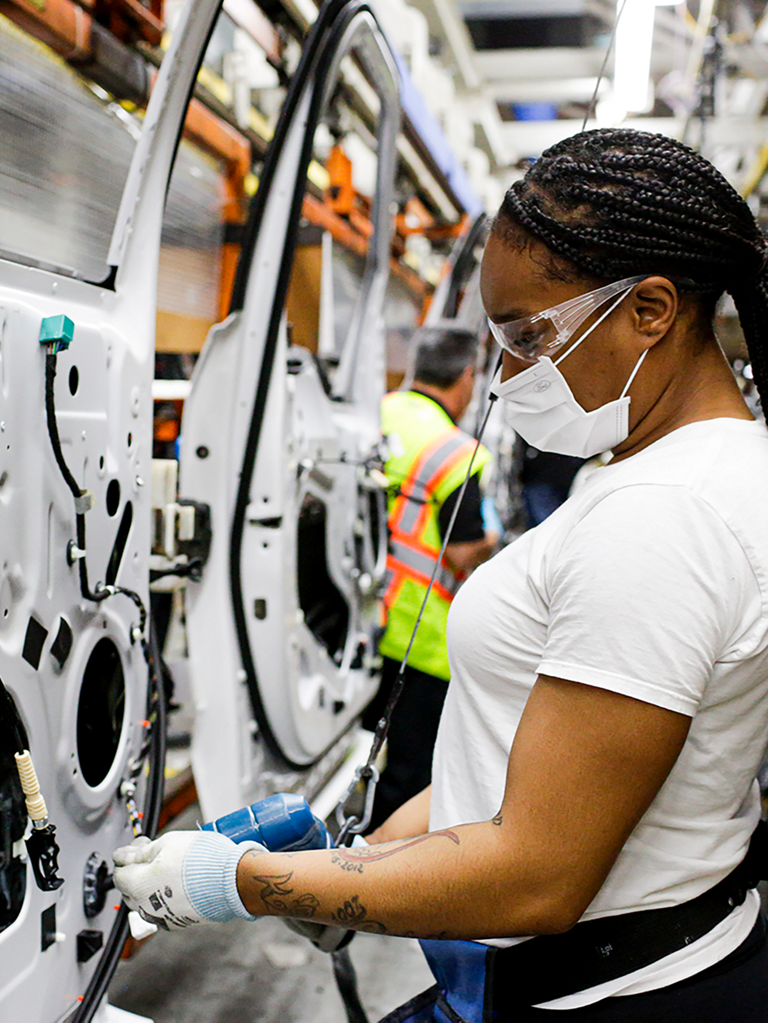 People working on vehicle doors on assembly line