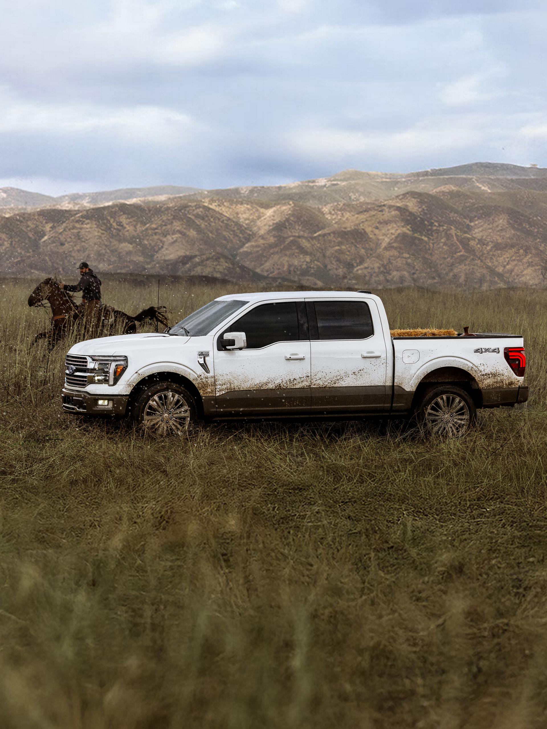 A person riding a horse near a mud splattered 2027 Ford F-150® King Ranch® parked in a field