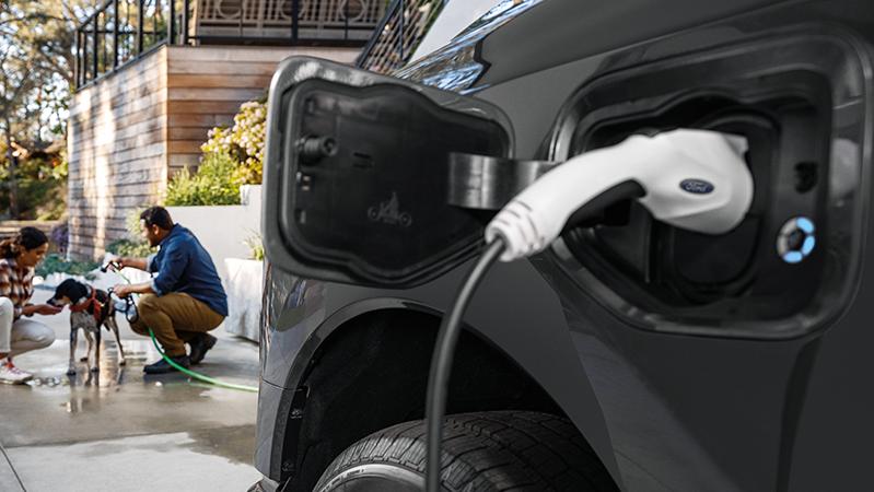 2025 Ford F-150 Lightning plugged into a Ford charger in driveway