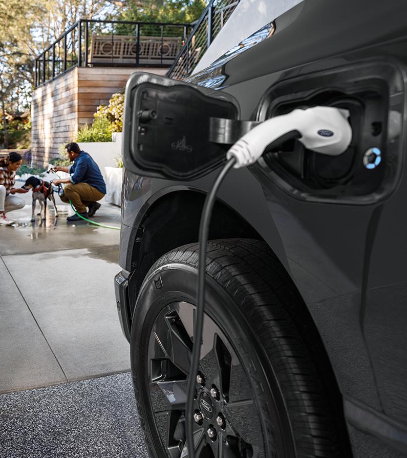 Ford F-150 Lightning plugged into a Ford charger in driveway 