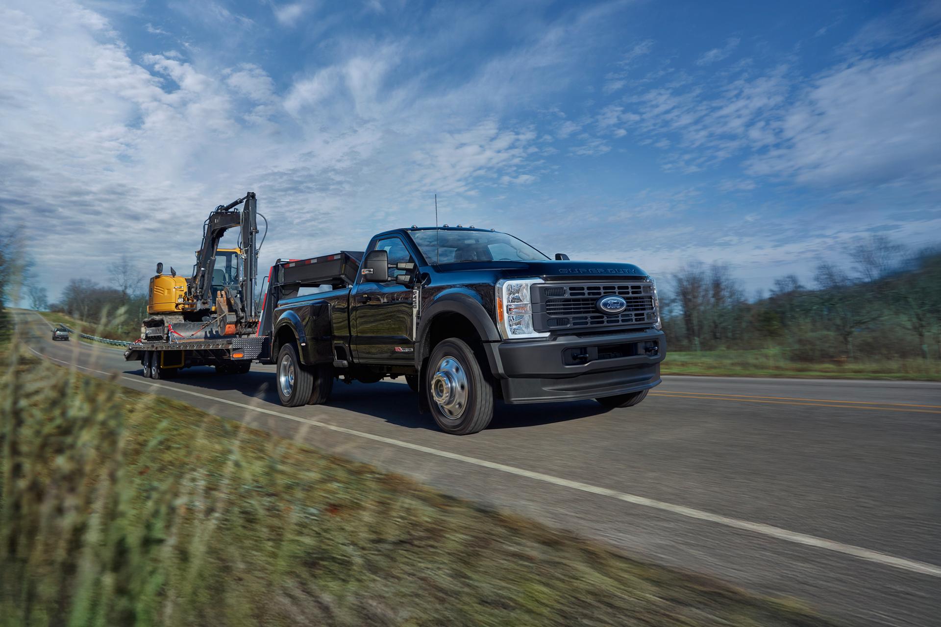 A diesel Ford Super Duty® truck towing an excavator on a two-lane road