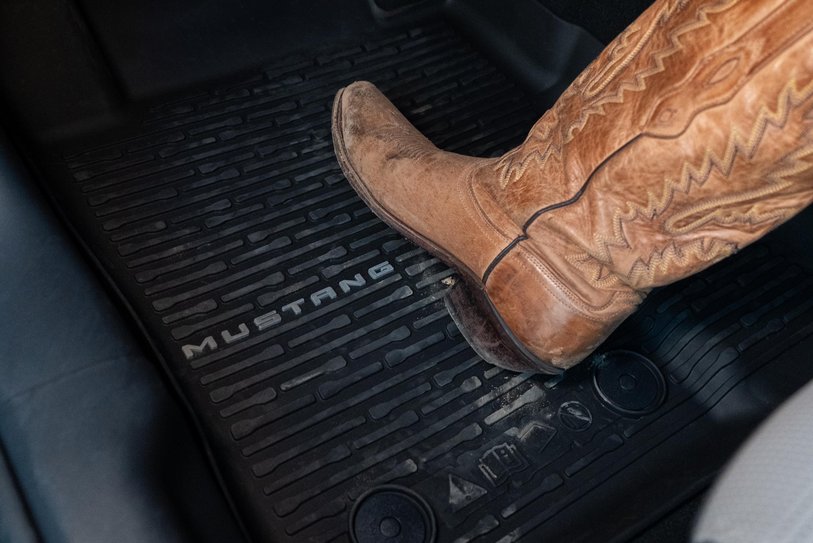 A Ford Mustang® logo all weather floor liner protecting the interior from dirt on a cowboy boot