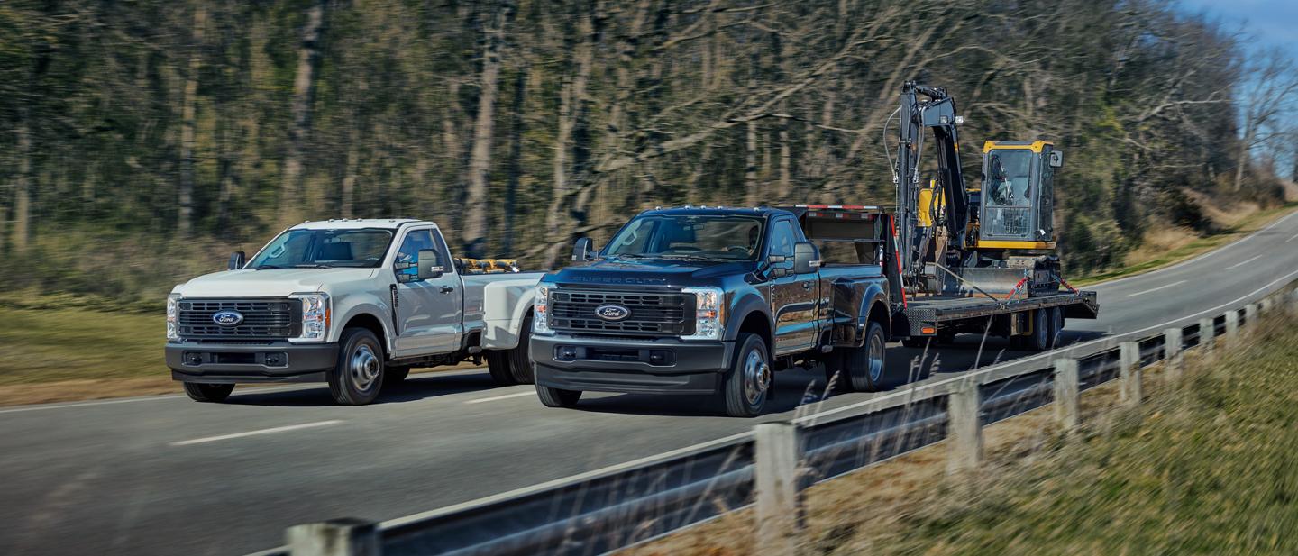2025 Ford Super Duty® F-350® XL DRW in Oxford White and F-450® XL DRW in Antimatter Blue being driven side by side on a paved road