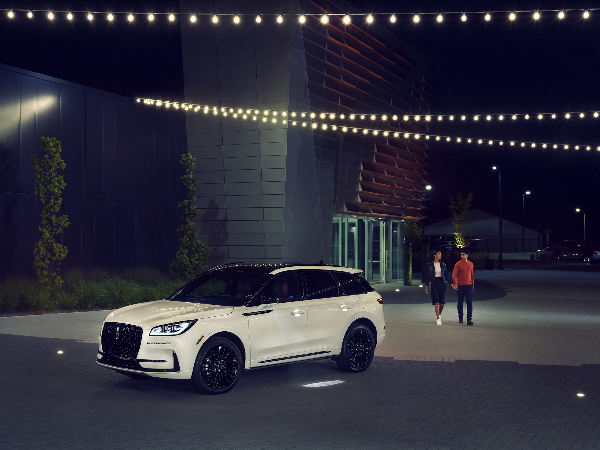 A couple approaches a 2025 Lincoln Corsair® Reserve model as the Lincoln Embrace illumination guides the way