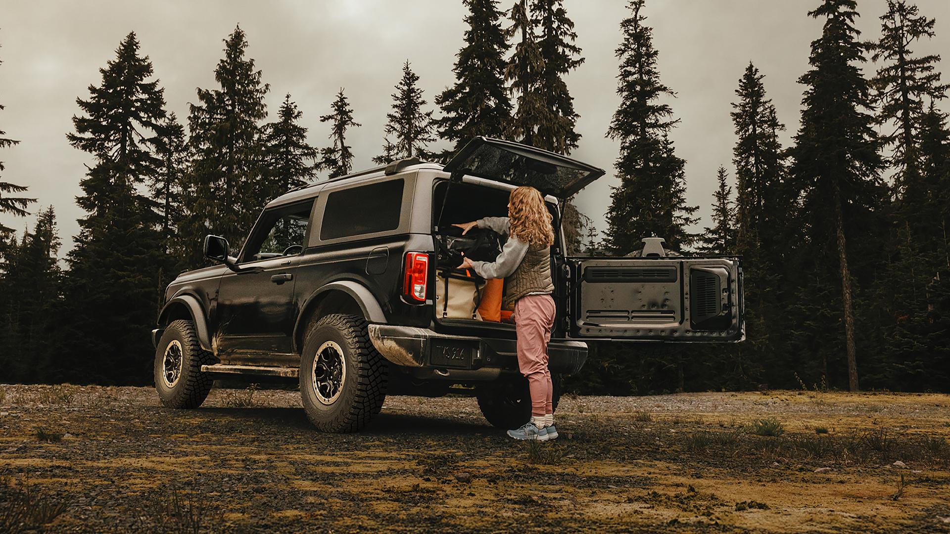 A woman unloading gear from the back of a 2026 Ford Bronco® SUV with the tailgate open