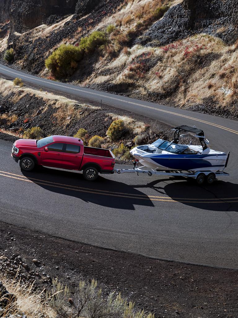 2026 Ford Ranger® XLT using the Advanced Towing Package to tow a boat on a winding mountain road