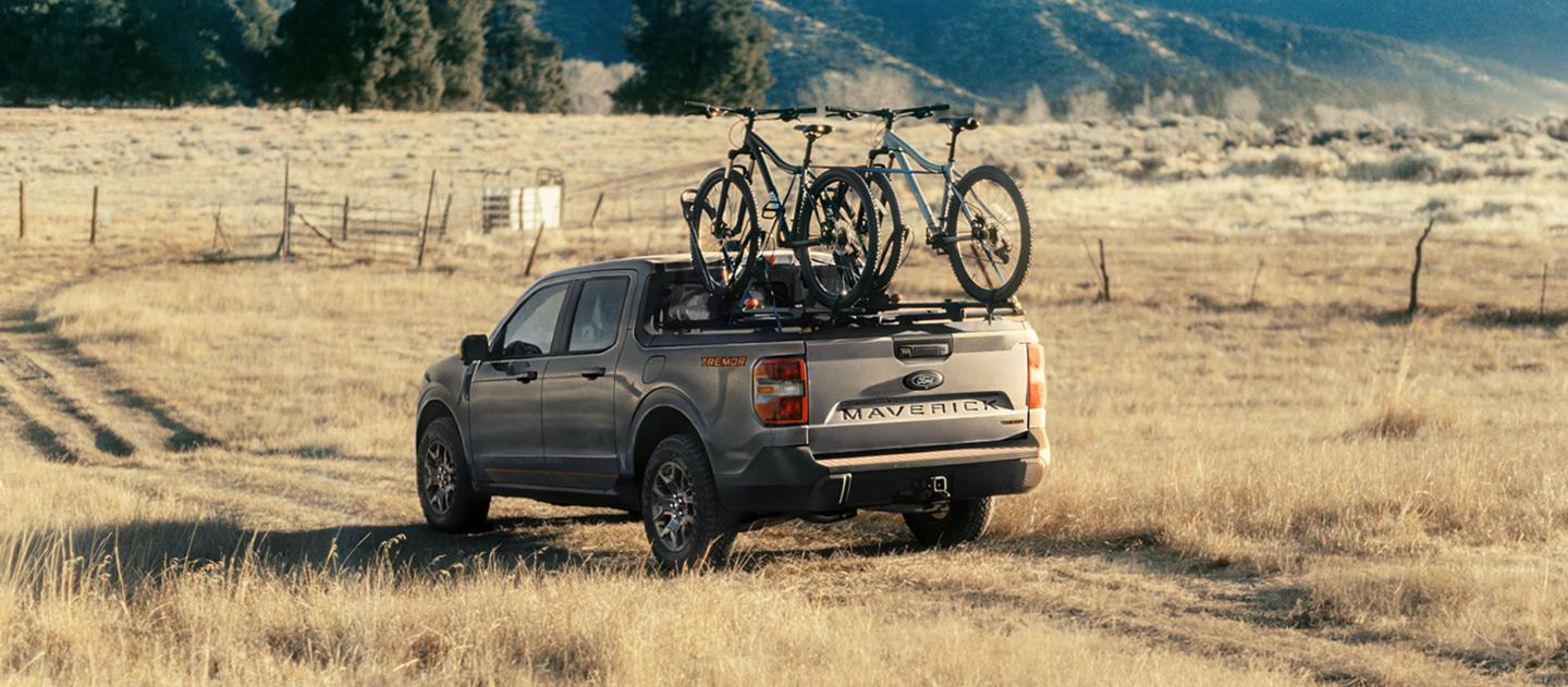 2026 Ford Maverick® Tremor® model being driven on a grassy field with bikes mounted in the bed