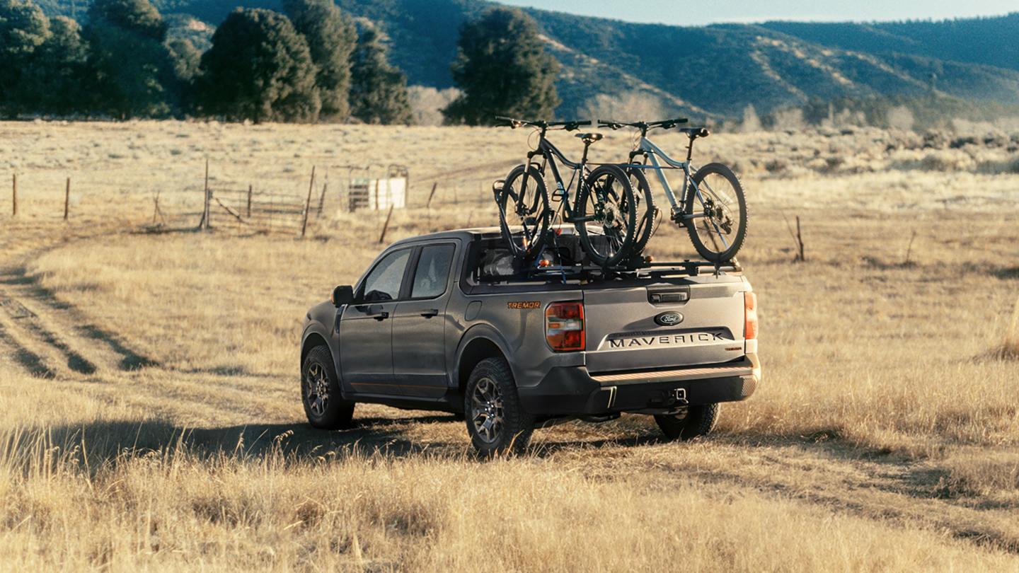 2026 Ford Maverick® Tremor® model being driven on a grassy field with bikes mounted in the bed