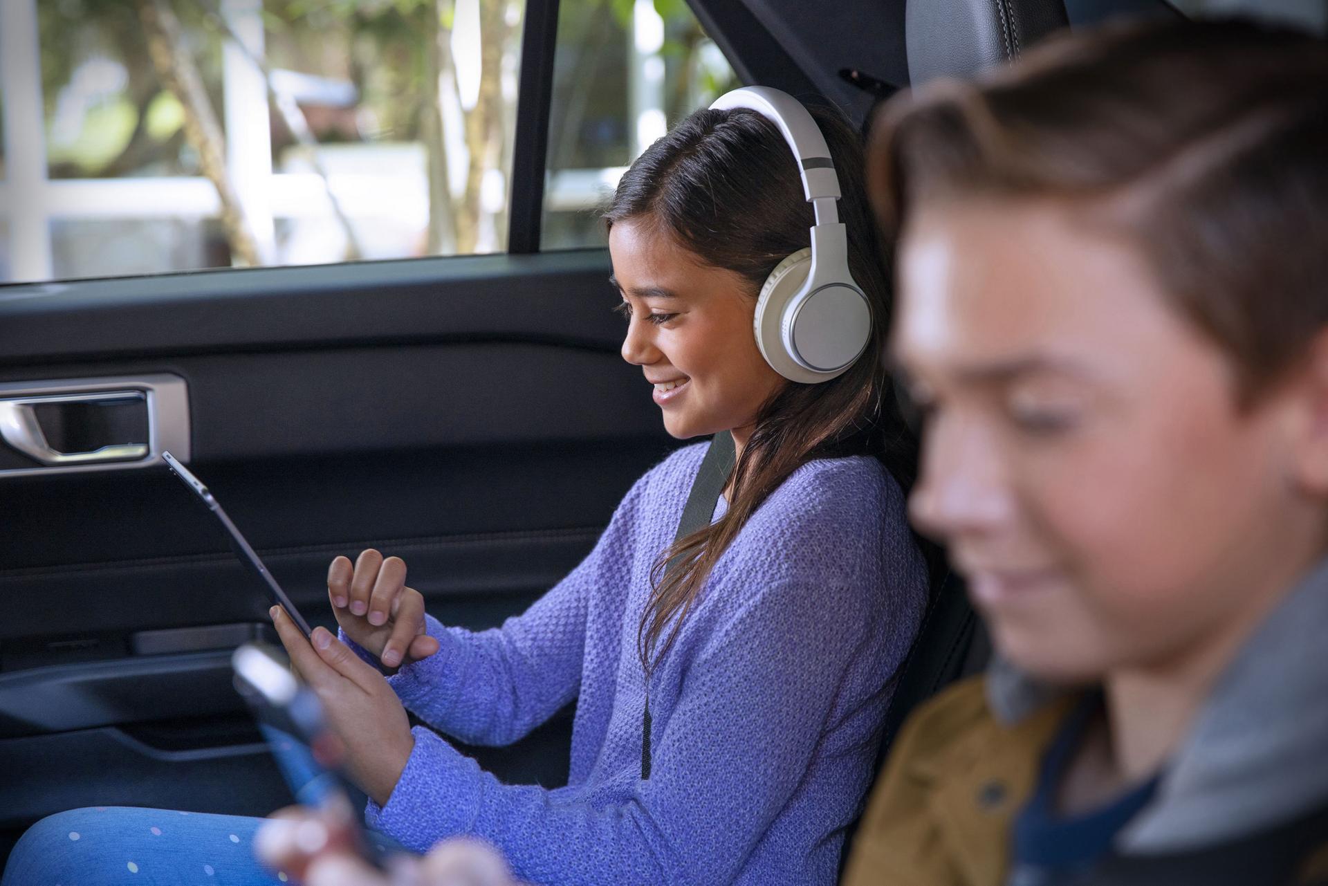 Back‑seat passenger using headphones and tablet because of Ford connectivity features