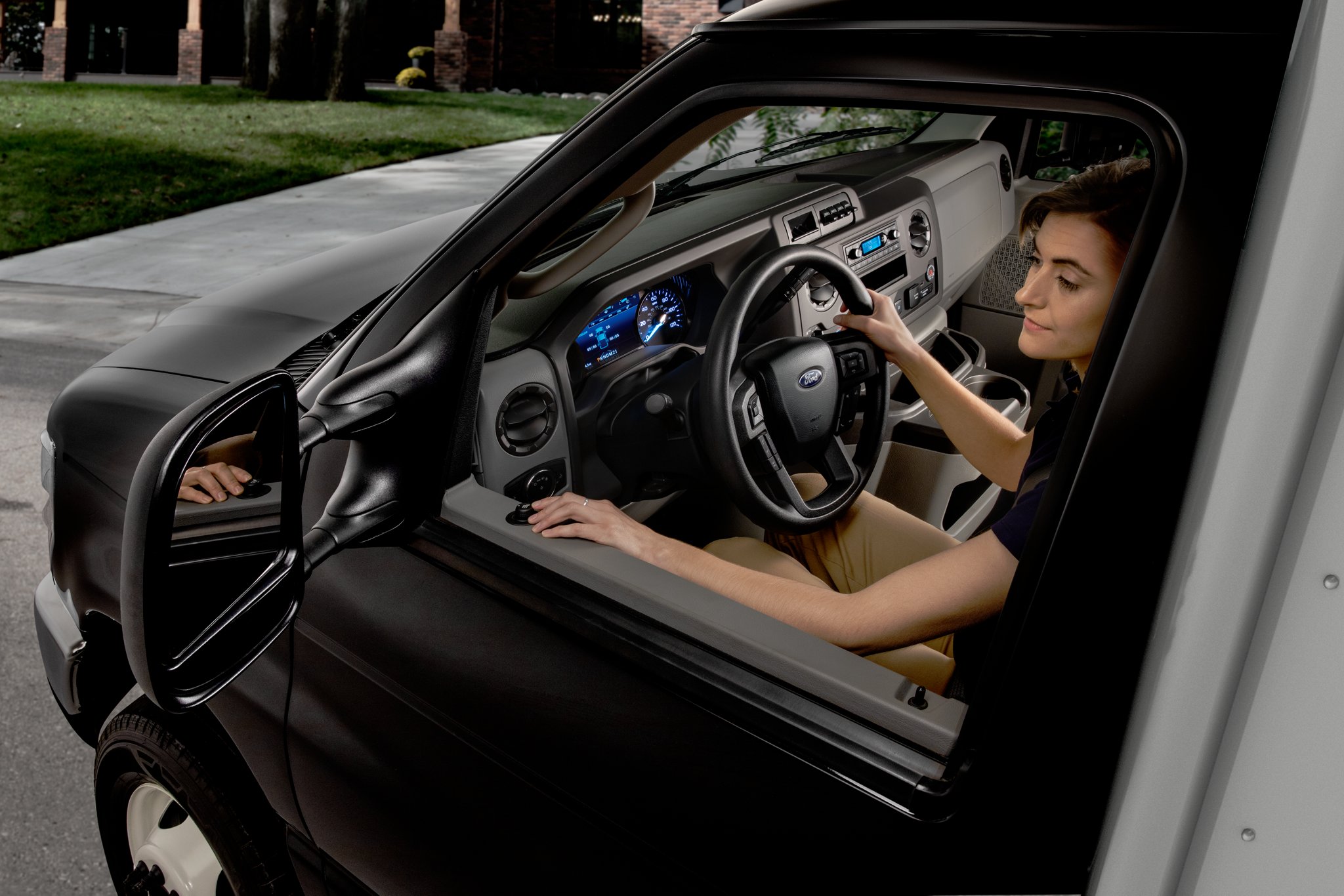 A woman adjusting the available telescoping trailer tow mirrors on the 2025 Ford E-Series Cutaway