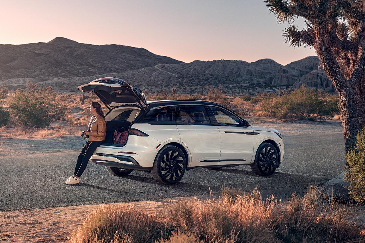 A photographer sits with the liftgate open on their Lincoln Nautilus® SUV while taking in the desert landscape