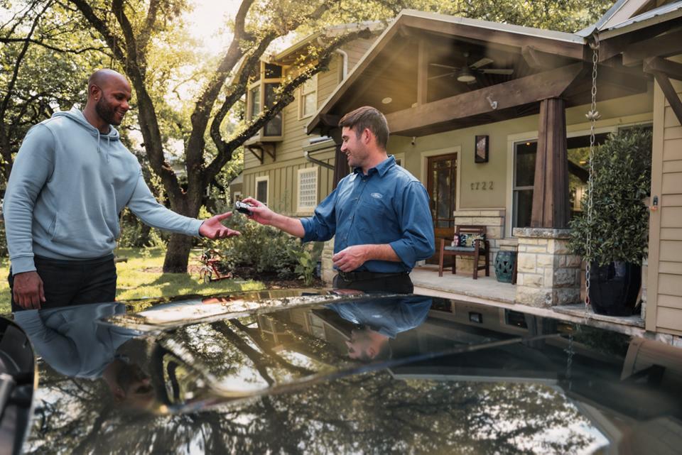 A Ford service tech hands a man his Ford key fob