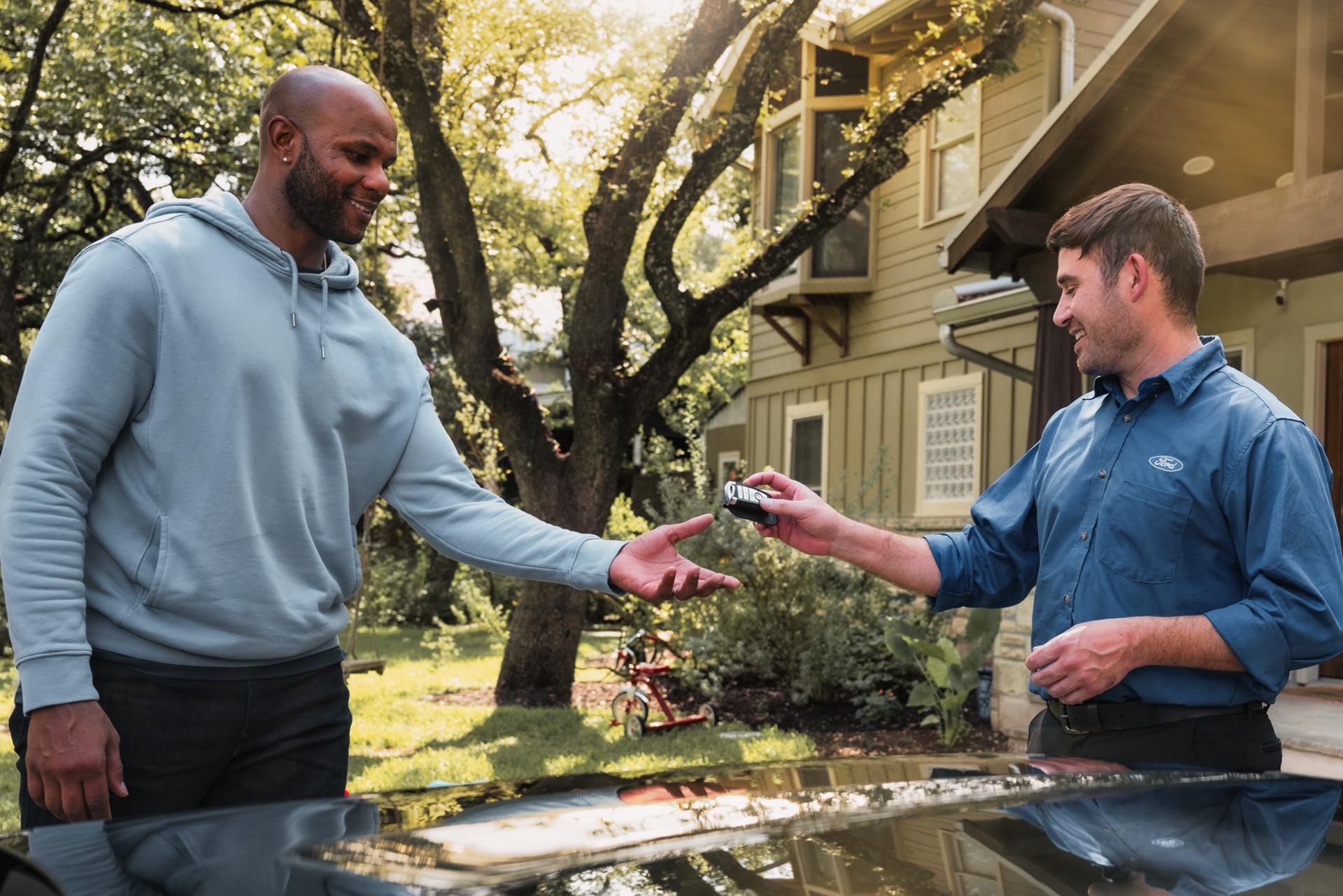 A Ford service tech hands a man his Ford key fob
