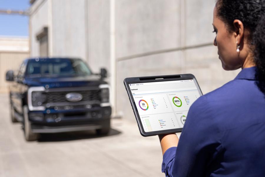 Woman looking at a tablet with a 2025 Ford Super Duty® XL STX® Appearance Package model parked in the background