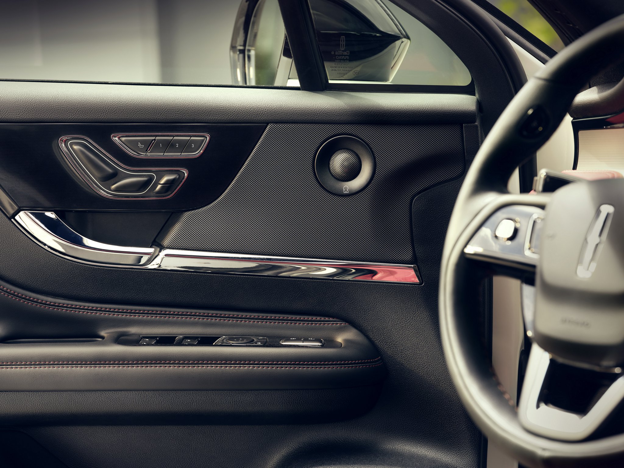 A mid-range speaker of the available 14-speaker Revel® Audio System is shown in the front driver's door panel