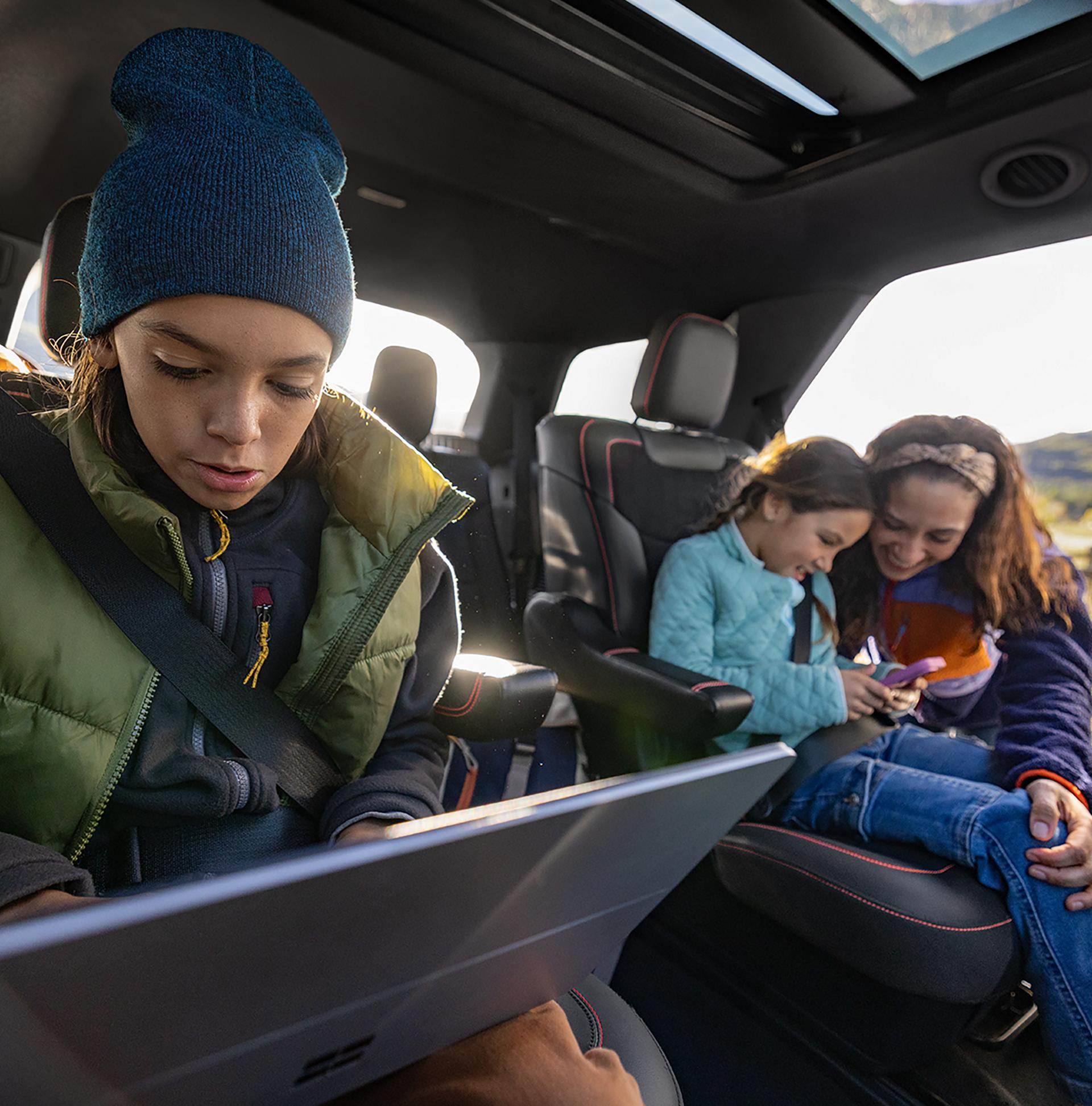 Two children using connected devices in the second-row seats of a 2027 Ford Explorer® SUV
