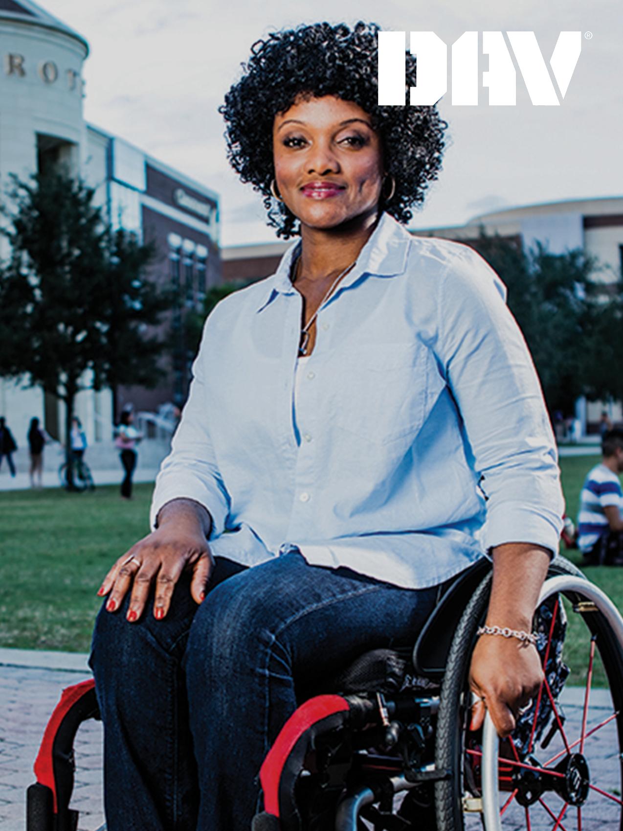 A veteran in a wheelchair smiles, a campus park in the background