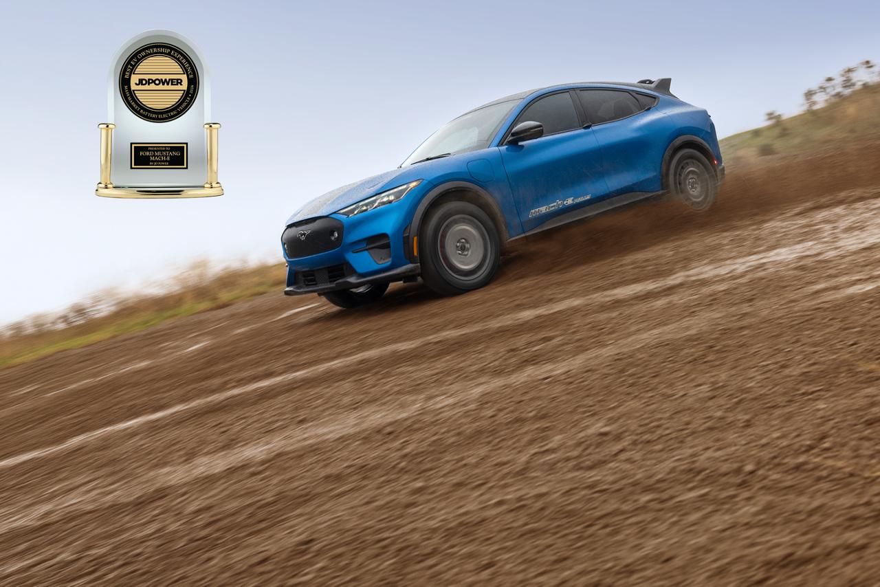 A blue 2026 Ford Mustang Mach-E® being driven down a rustic dirt path