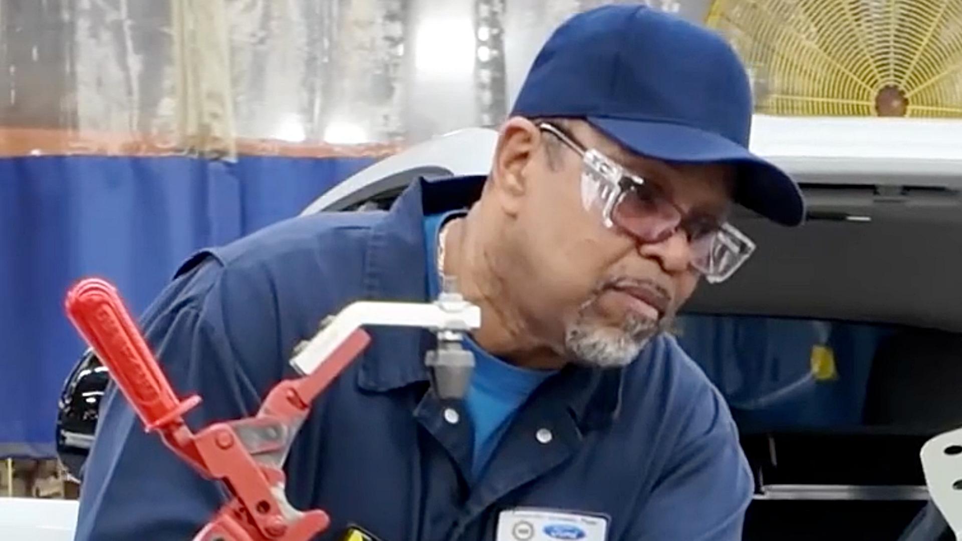 A man in a hat, wearing glasses working on a prototype of the vehicle