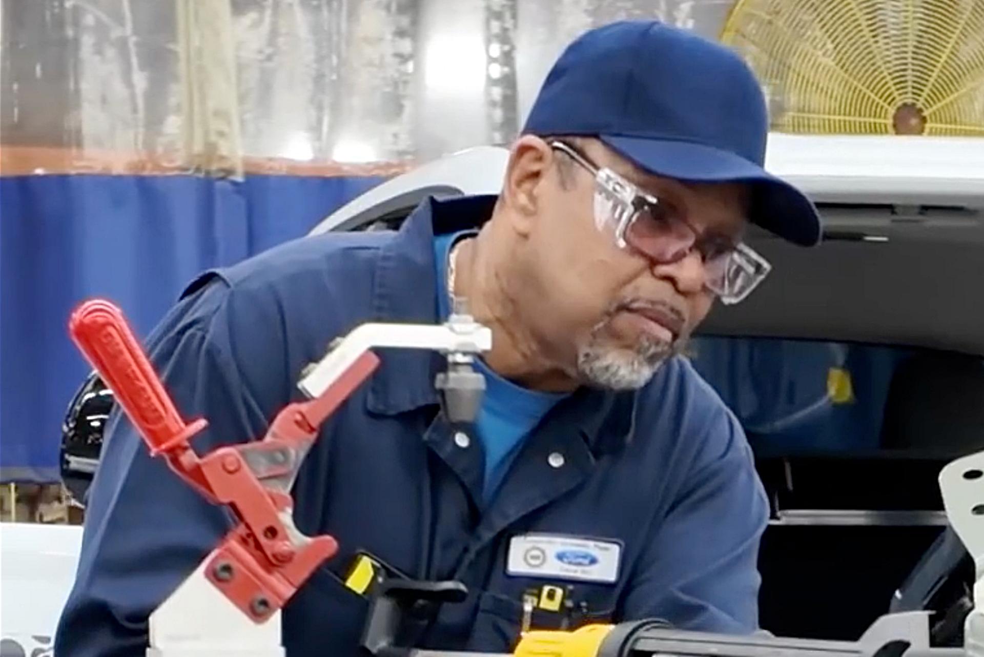 A man in a hat, wearing glasses working on a prototype of the vehicle