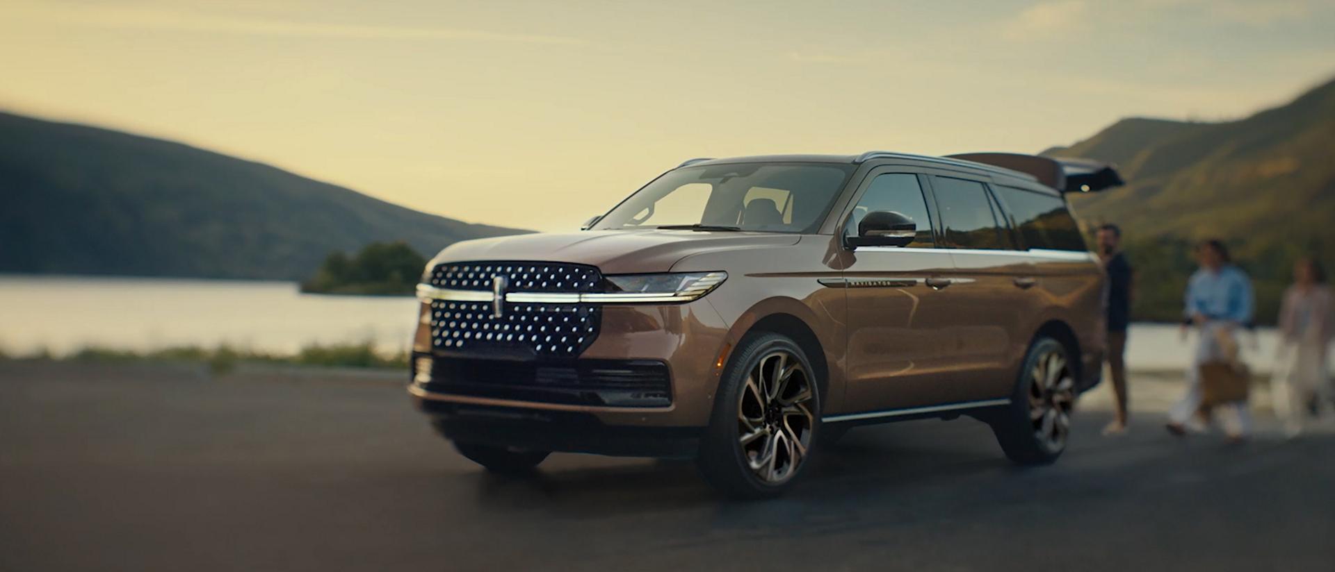 Una familia se acerca a una Lincoln Black Label Navigator 2026 y comienza la secuencia de luces Embrace