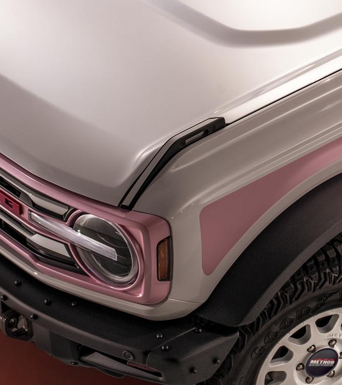 Front three-quarter view of a white Bronco highlighting the pink painted trail sights on the front fenders.
