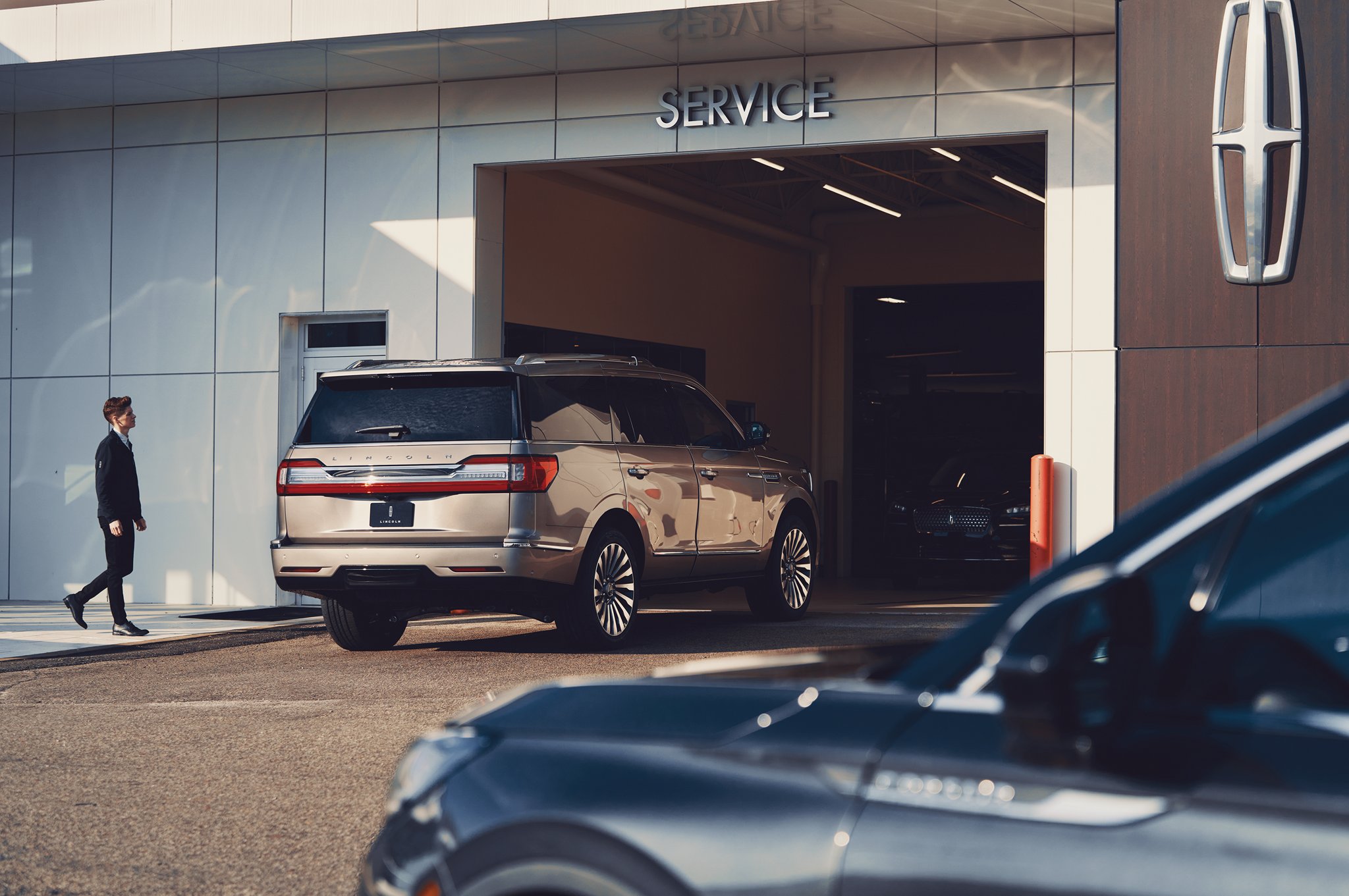 A Lincoln vehicle driving into the service center at a Lincoln retailer.