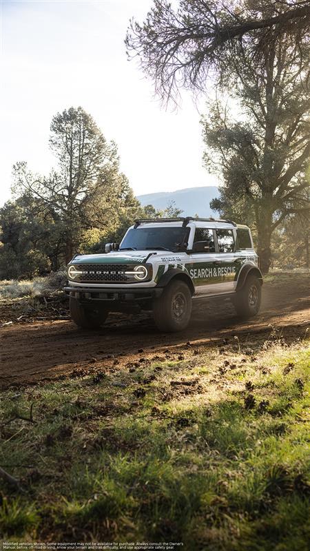 A white 2026 Ford Bronco® SUV labeled as Search & Rescue driving on a dirt path