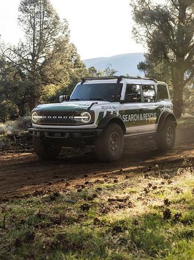 A white 2026 Ford Bronco® SUV labeled as Search & Rescue driving on a dirt path