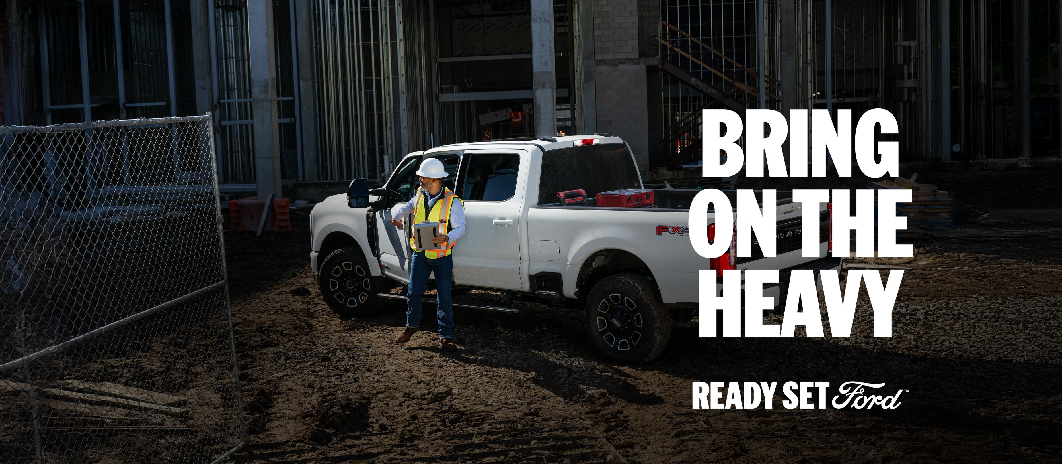 A manager stands outside their 2026 Ford Super Duty® truck at a build site