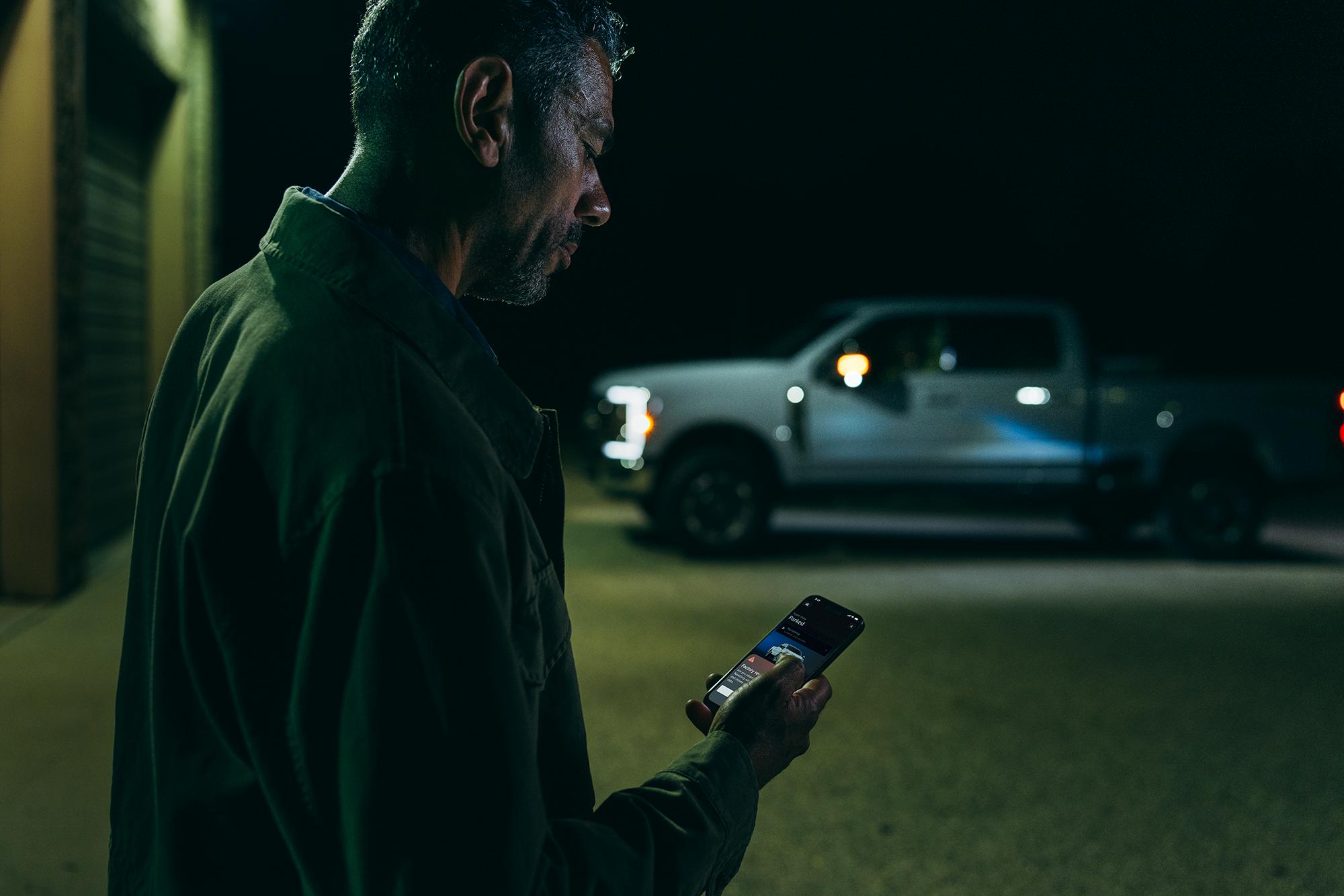 A man standing outside looking at his phone with an F-150® truck in background