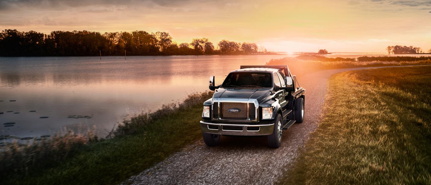 2026 Ford F-750® Crew Cab in Agate Black with utility stake bed upfit being driven near a lake