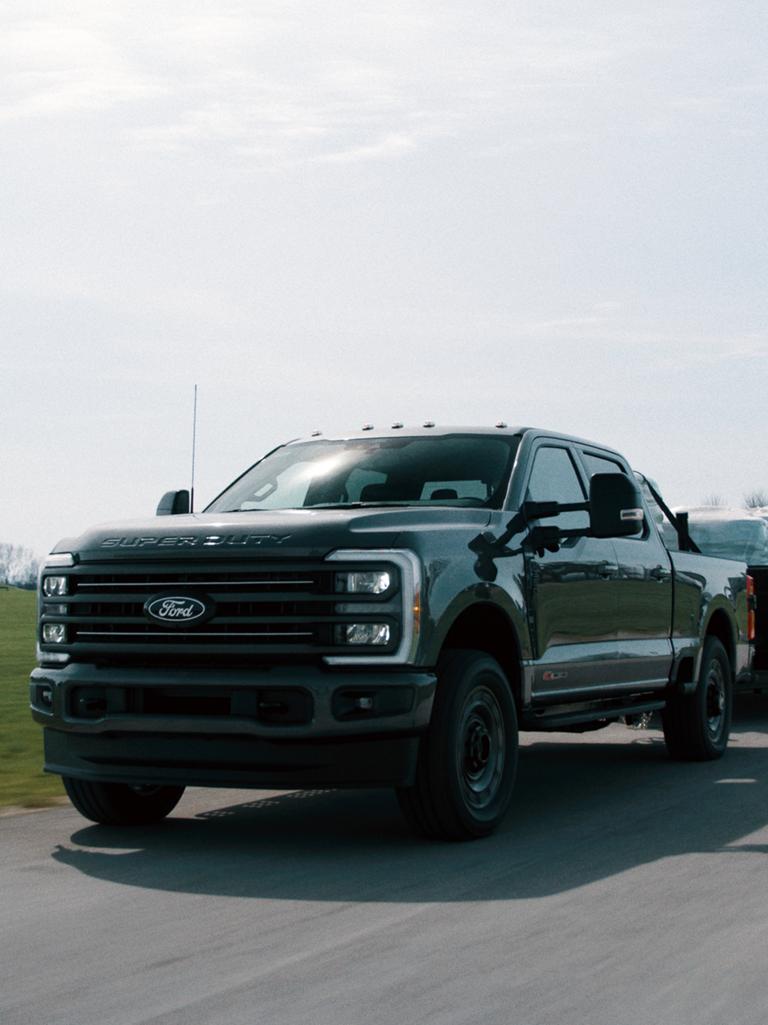 2027 Ford Super Duty® F-350® XLT model with the Super Duty Carhartt® Package towing a flatbed trailer