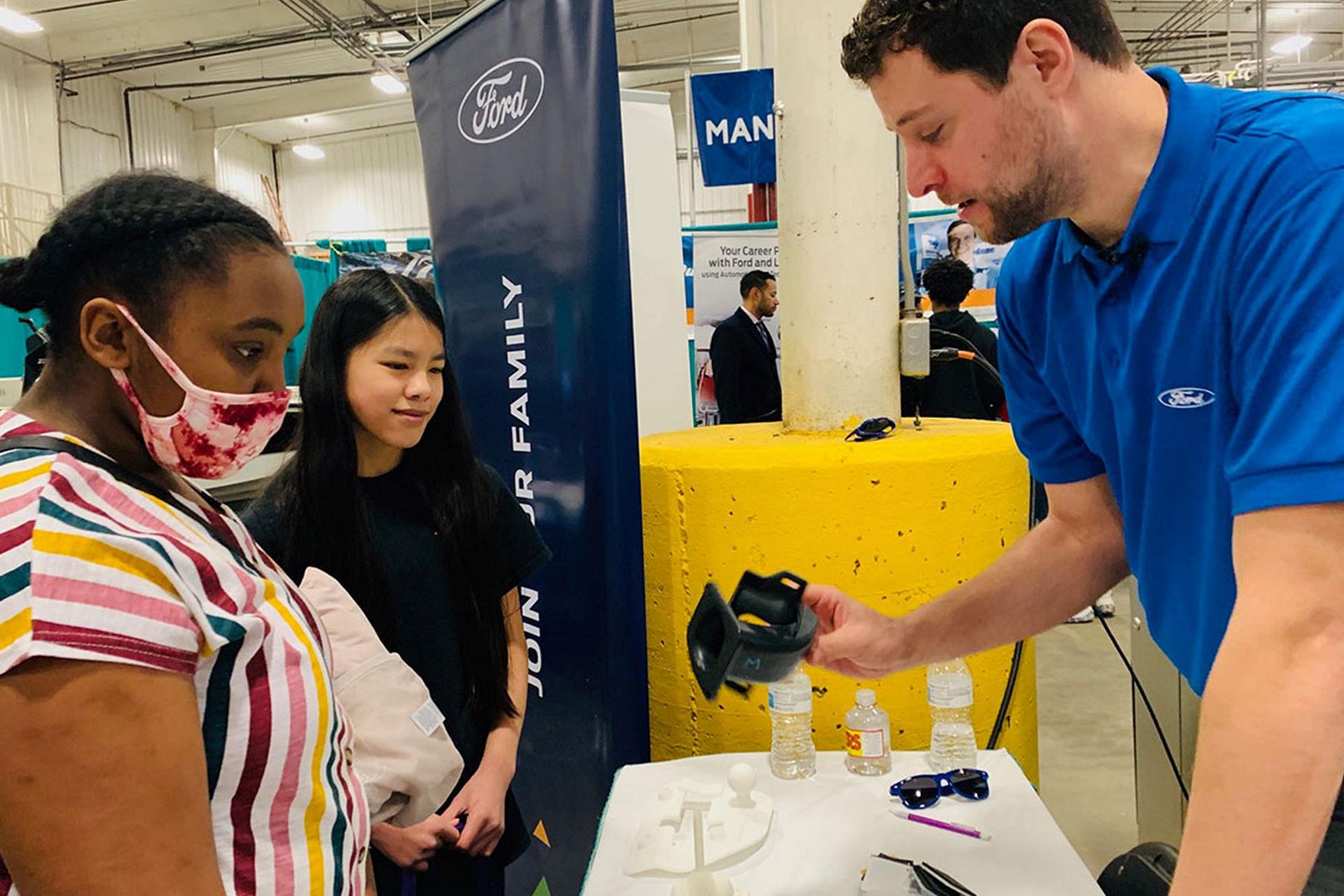 A Ford employee talks to students at a school career fair