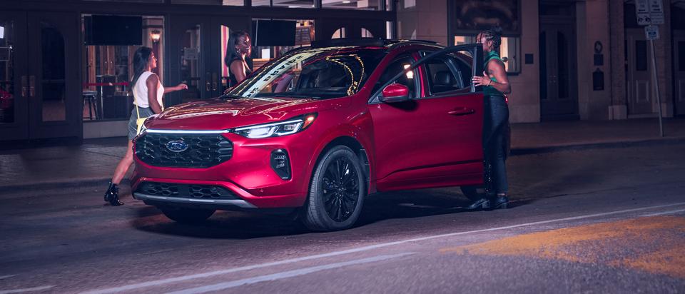 A group of friends get into a red 2025 Ford Escape® SUV at night