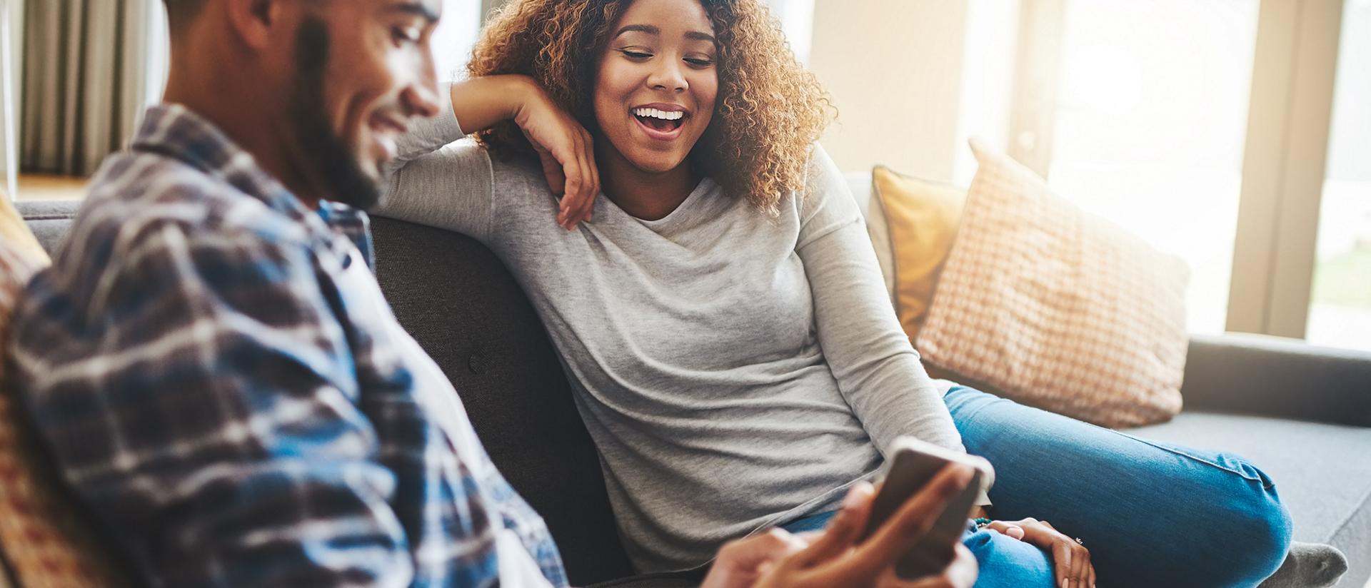 A couple sit on their couch chatting with their Ford Advisor