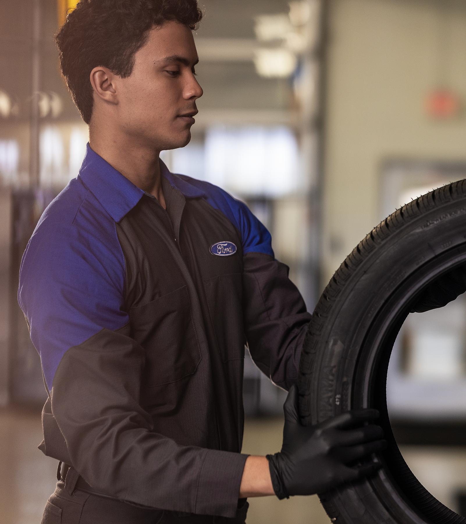 A Ford Service technician with a new tire