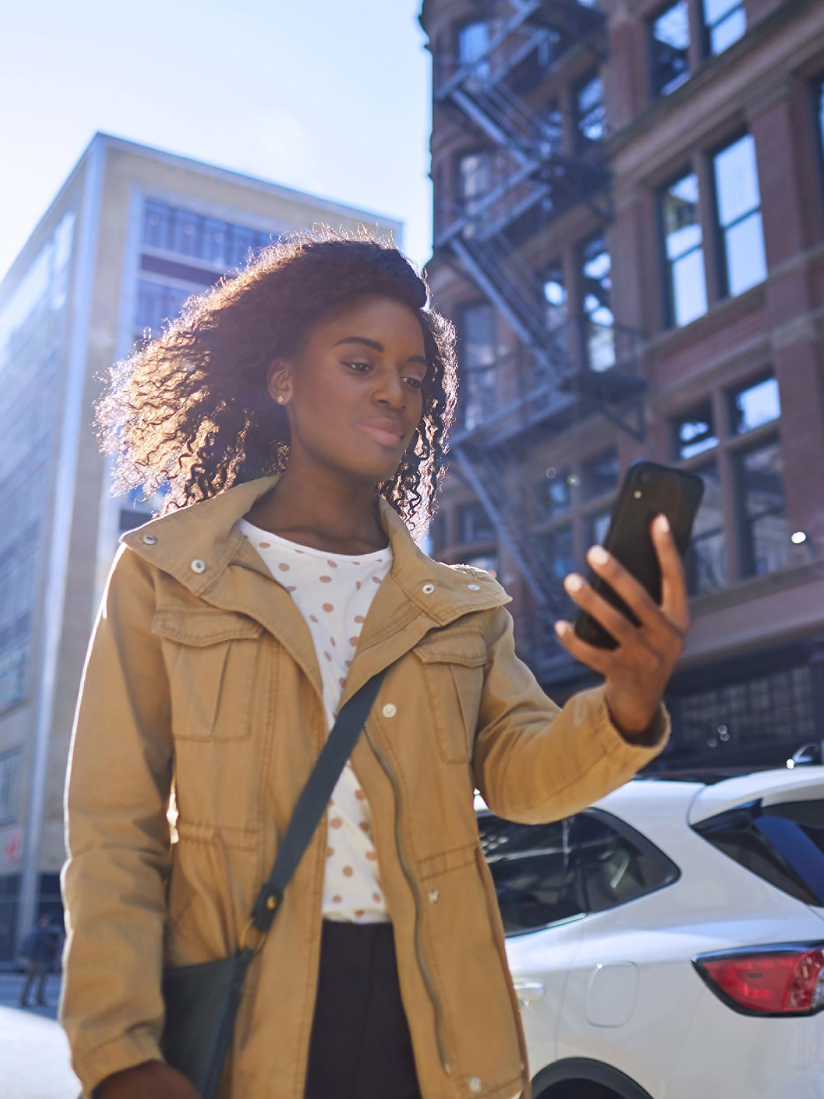Woman walking in a city looking at her phone