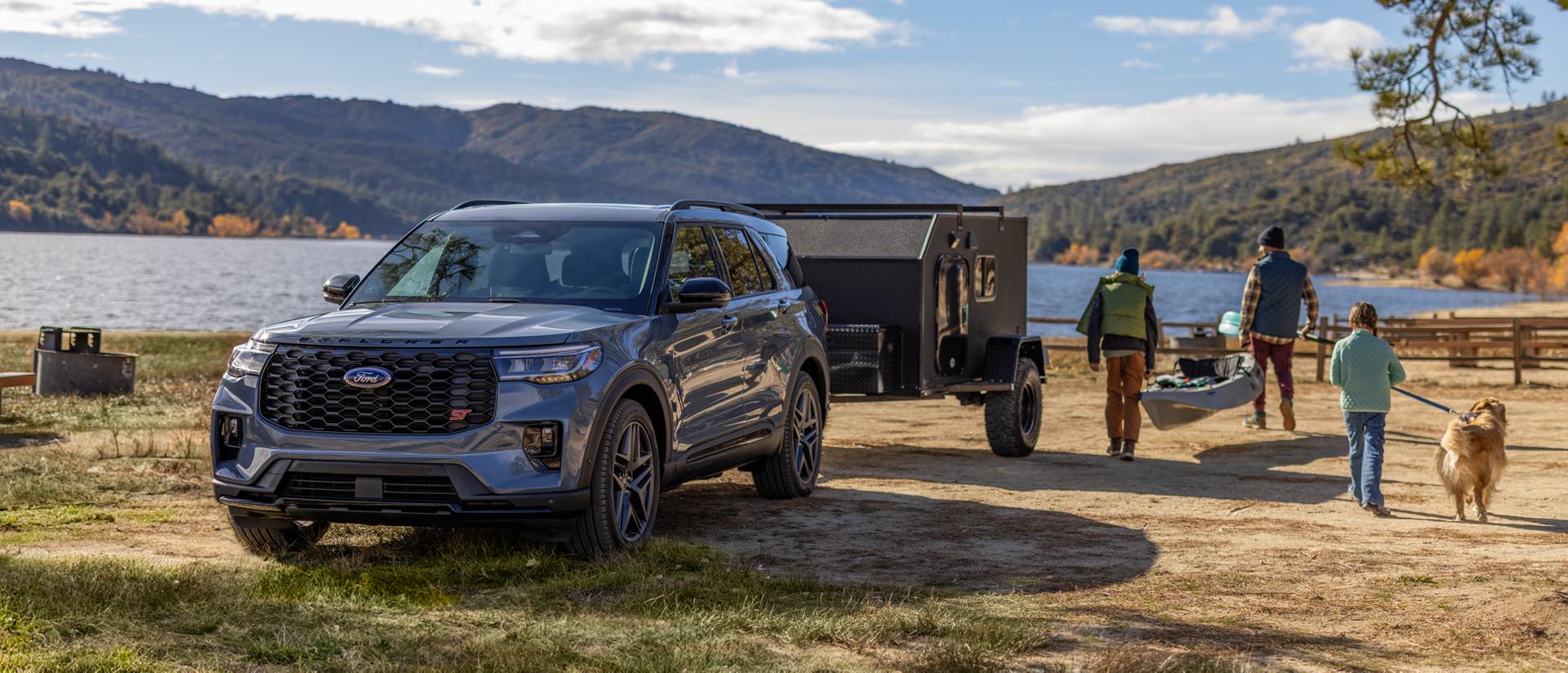 A family and their dog walking away from a 2026 Ford Explorer® SUV carrying recreational equipment