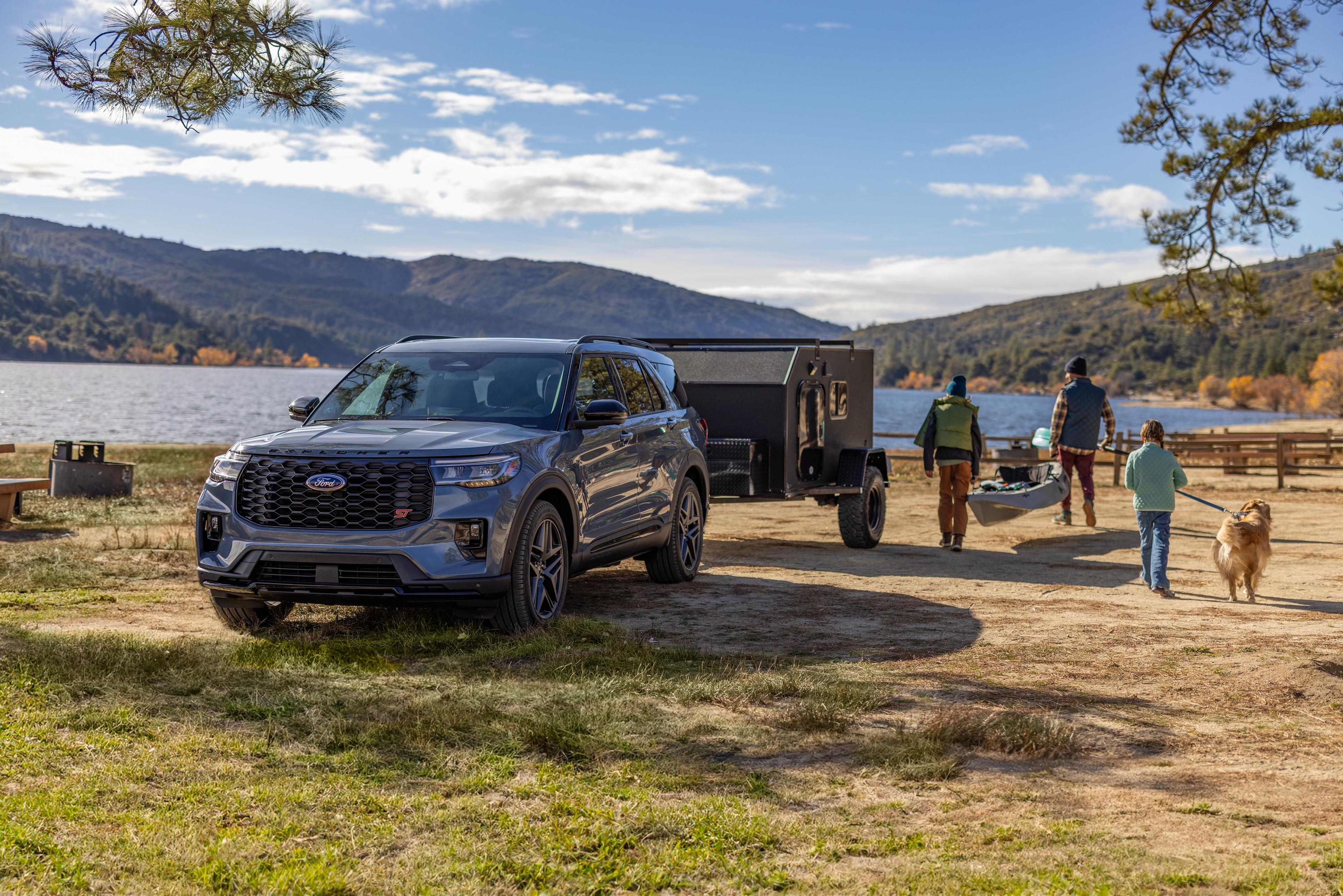 A family and their dog walking away from a 2026 Ford Explorer® SUV carrying recreational equipment