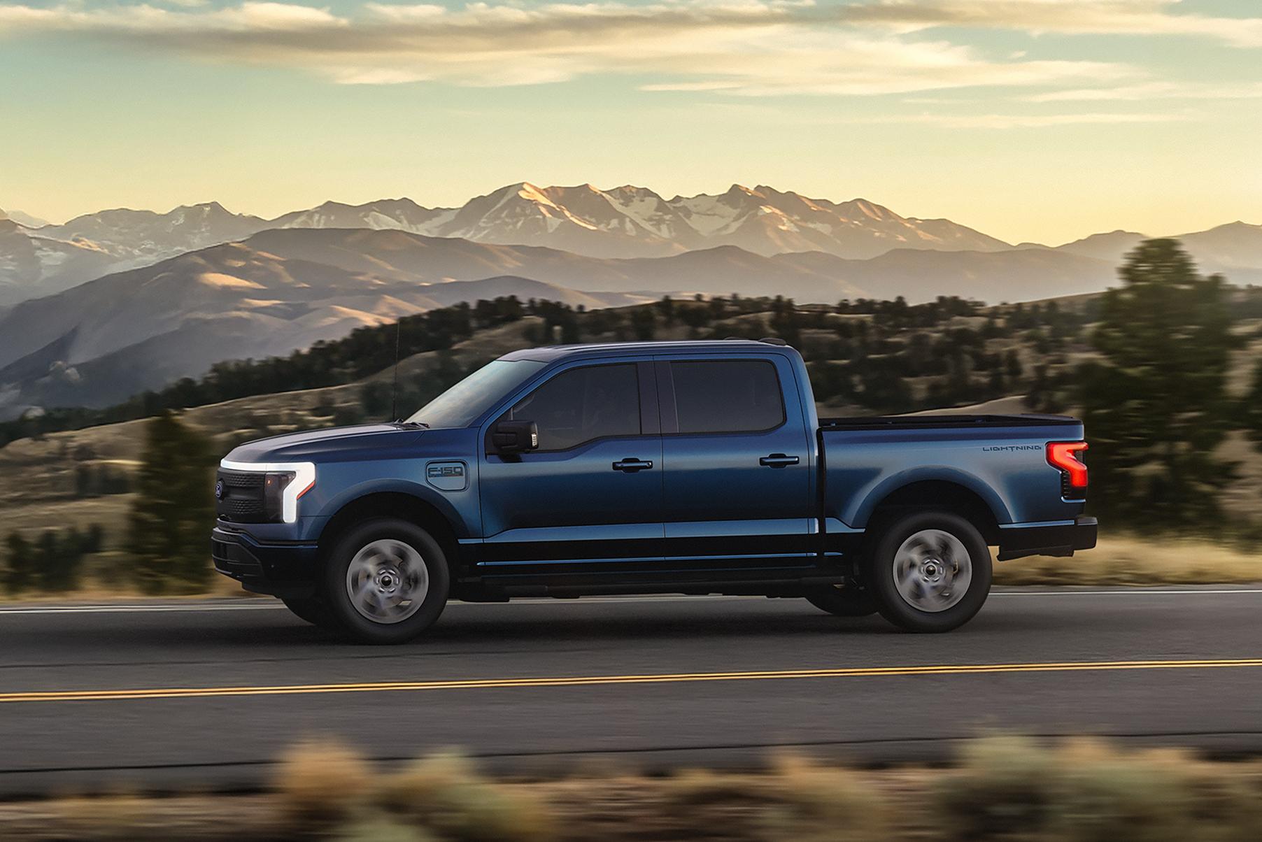 2025 Ford F-150® Lightning® driving down road with mountains in background