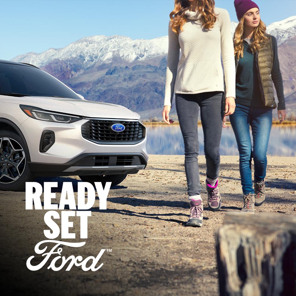A white 2026 Ford Escape parked with mountains in the background and two women walking