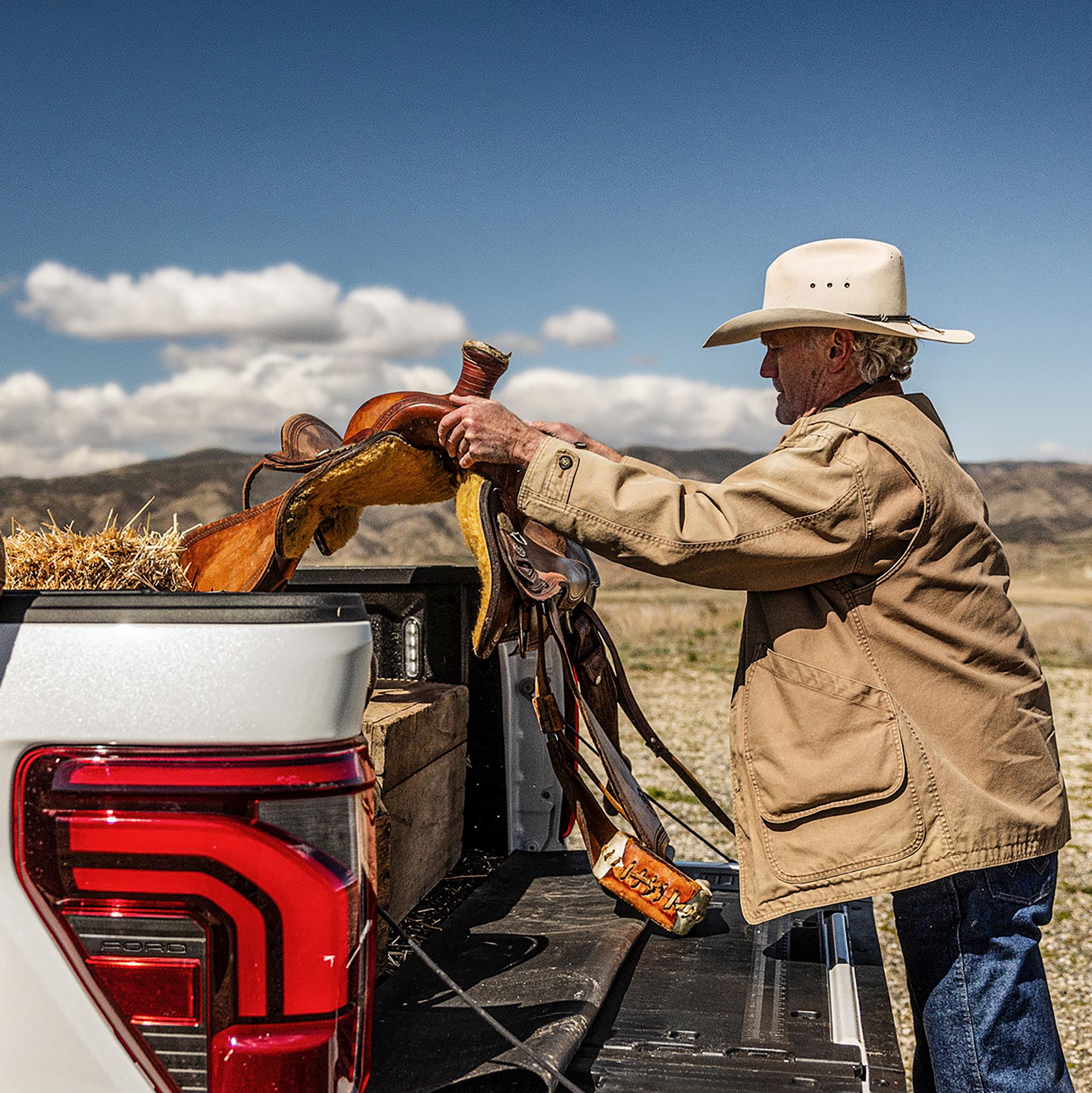 A person unloading a saddle from the bed of their 2025 Ford F-150®
