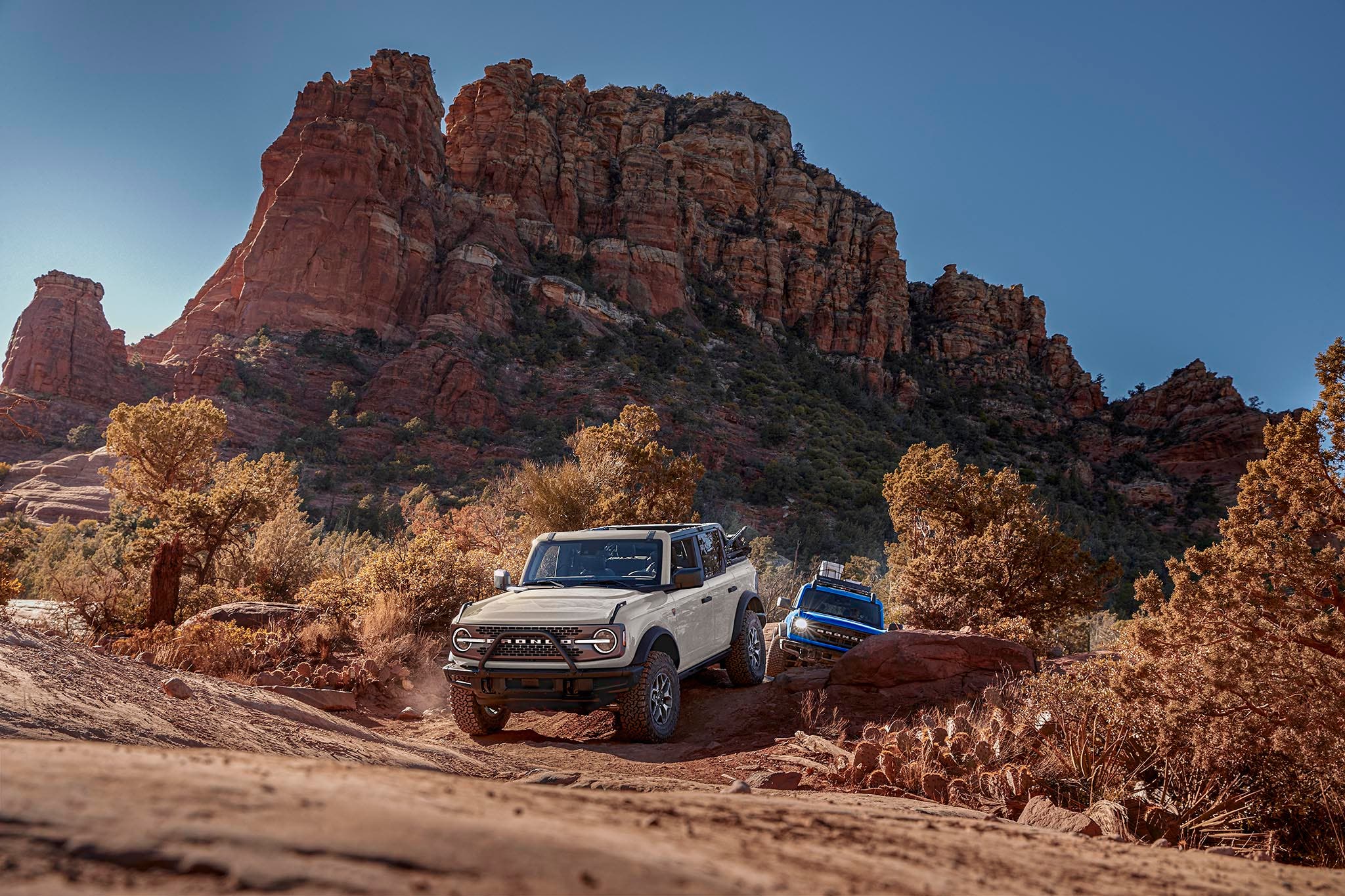 White 2025 Ford Bronco® navigating a rocky dirt road in a red rock desert canyon