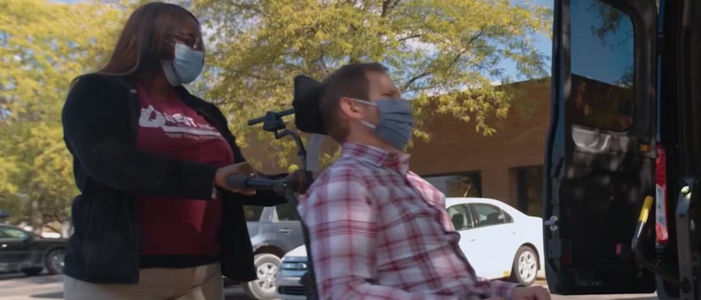 Woman behind a man in wheelchair behind a Ford Transit® van