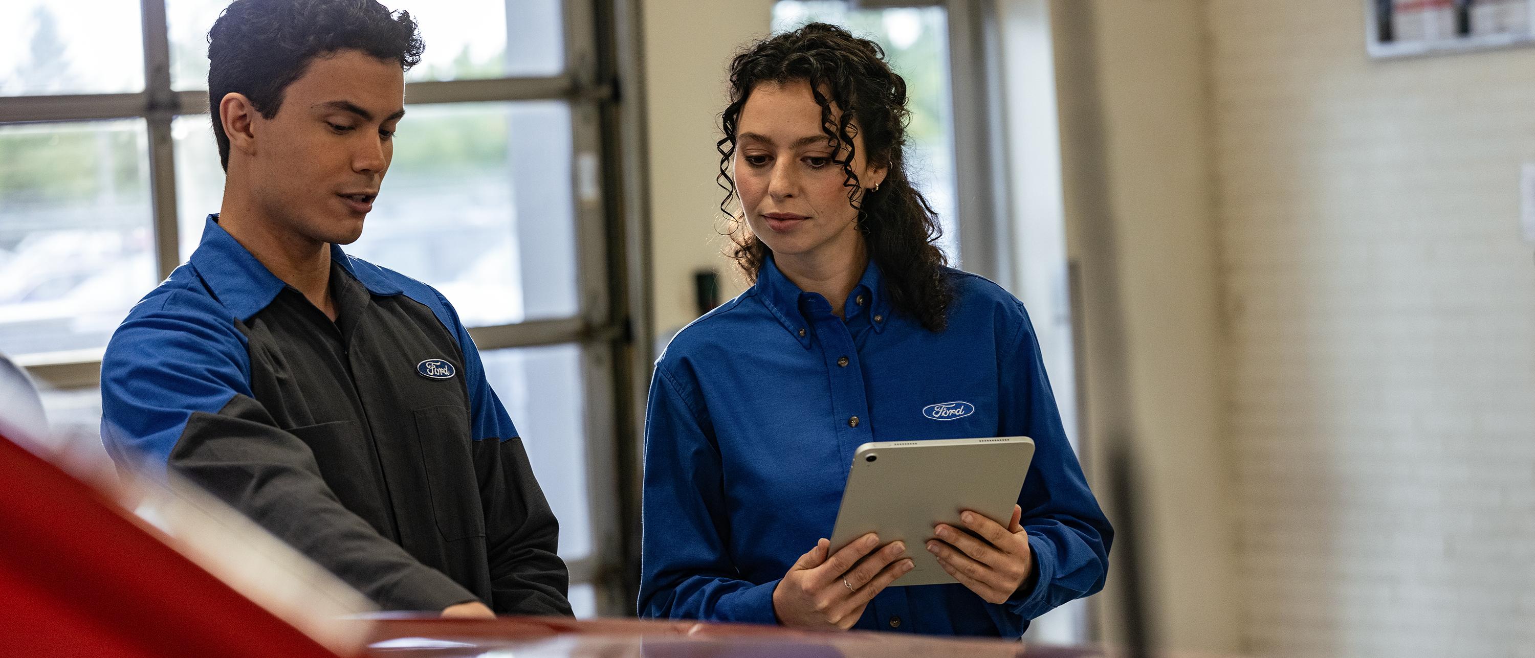 Two Ford technicians service a vehicle at a Collision Center